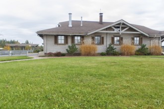 Modern wooden cottage with green lawn and landscape design with ornamental grasses and pines