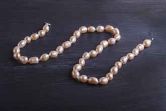 Caramel colored pearl beads on a black background. top view, close up