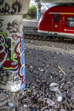 Empty spray paint cans, on a railway line below a road bridge, thrown away, disposed of by the