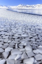 Ice floes on a lake in front of snow-covered mountains, sun, snow, winter, Snaefellsnes,