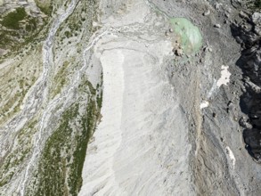 Stream flowing from a glacial lake breaks through a large moraine, valley Val Ferret, aerial view,