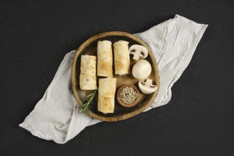 Thin pancakes stuffed with mushrooms on a wooden plate. The rustic setting enhances the appetizing