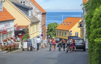 People with bicycles on sloping street in Gudhjem, Denmark, Baltic Sea, Scandinavia, Europe