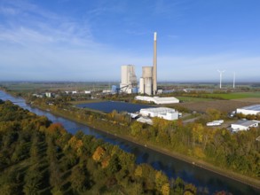 A coal-fired power plant in a rural landscape, with wind turbines and a canal along colourful