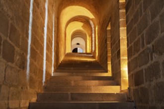 Stone vaulted staircase with warm lighting in an antique setting, Le Mont-Saint-Michel