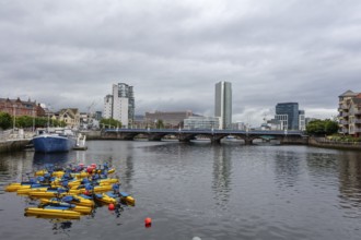 City view with skyscrapers and bridge over a river on which boats are floating, Belfast