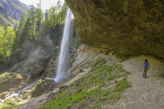 Woman walking behind the cascade of the Pericnik waterfall, Mojstrana, Kranjska Gora, Slovenia,