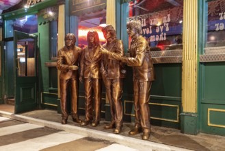 Bronze statues of four people in front of a traditionally decorated building, Liverpool