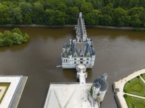 Aerial view of a castle in the river Cher, surrounded by dense forest with a view of the water and