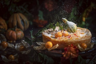 Icing sugar falls on autumnal cake with yellow physalis and pumpkin, romantic atmosphere