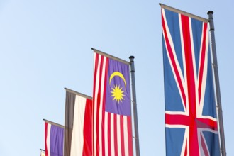 Various national flags fly on flagpoles against a blue sky, Malaysian flag, English flag, Egyptian