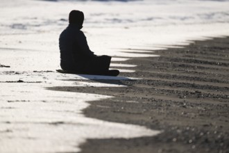 Meditating woman, snowy beach, Spitsbergen Island, Svalbard and Jan Mayen archipelago, Norway,