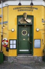 Green entrance door with ship's propeller, yellow painted façade, Christianshavns Færgecafé,