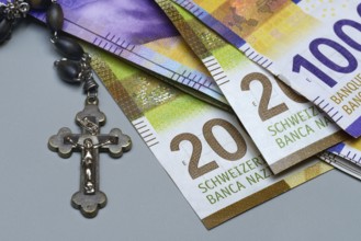 Crucifix and banknotes, Swiss francs, church and money