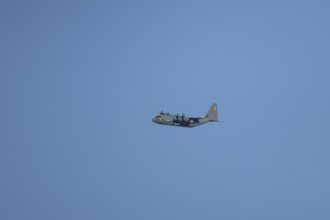 Lockheed C-130 Hercules military aircraft of the USAF United States air force flying in a blue sky,