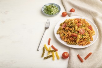 Tortiglioni semolina pasta with tomato and microgreen sprouts on a white wooden background and