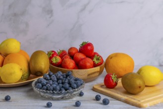 Harmonious still life of various fruits, strawberries, lemons, oranges, kiwis and blueberries on