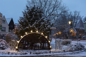 Candle arch on the main street, snow-covered and at dusk, in the background the old church, Coswig,