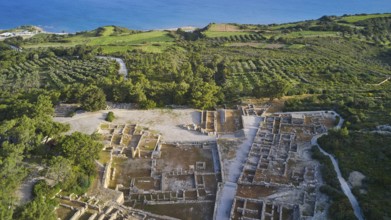 Drone shot, first morning light, aerial view of ancient ruins near the coast, surrounded by green