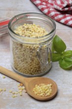 Fregola in wooden spoon and glass container, pasta variety from Sardinia, Italy, Europe