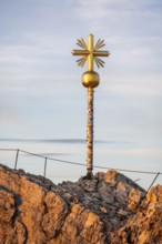 Summit of the Zugspitze with golden summit cross, alpenglow at sunset, Northern Limestone Alps,