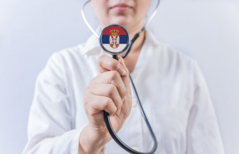 Female doctor holding stethoscope with Serbia flag. National Health System of Serbia