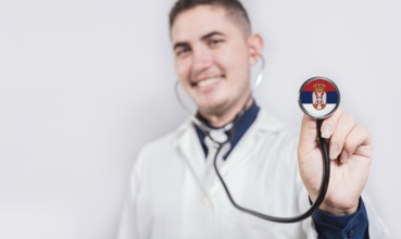 Happy doctor showing stethoscope with Serbia flag. Serbia National Healthcare concept