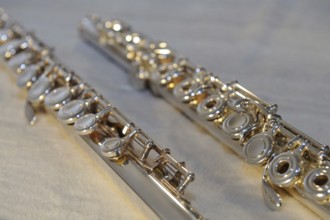 Close-up of two silver transverse flutes on a light-coloured surface