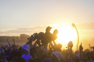 A wheelchair user crowdsurfing in front of sunset at the Highfield Festival on Friday, Störmthaler