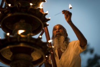 Old man lights oil lamp for Hindu fire ceremony Aarti, Ambalapuzha, Kerala