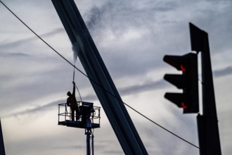 Worker cleans a bridge pier with a high-pressure cleaner on a cherry picker at the Erasmus Bridge