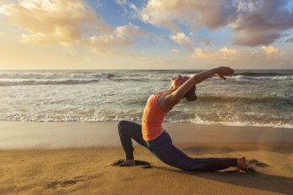 Yoga outdoors, sporty fit woman practices yoga Anjaneyasana, low crescent lunge pose outdoors at