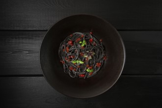 Black spaghetti with red caviar, pasta, on a black background, top view, no people