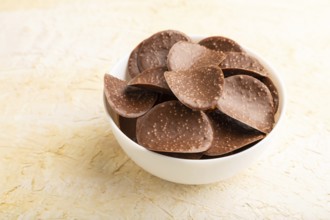 Chocolate chips with caramel on a beige concrete background. side view, close up