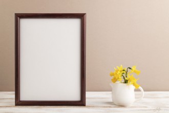 Wooden frame with spring snowdrop flowers narcissus on beige pastel background. side view, copy