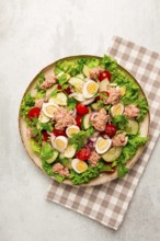 Tuna salad, vegetable salad with quail eggs, lettuce, red onion and cucumbers, on a light gray