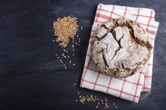 Yeast free homemade bread with whole rye and wheat grains on black wooden background. Top view,