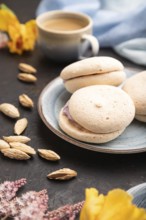 Meringues cakes with cup of coffee on a black concrete background and blue linen textile. Side