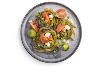 Tagliatelle green spinach pasta with tomato, pea and microgreen sprouts isolated on white