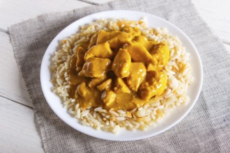 Rice with chicken curry sauce with cashew on white wooden background. top view, close up