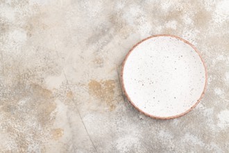 Empty white with dots ceramic plate on brown concrete background. Top view, copy space, flat lay