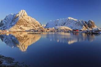 Snow-covered mountains reflected in fjord at sunrise, village, winter, Reine, Moskenesoya, Lofoten,