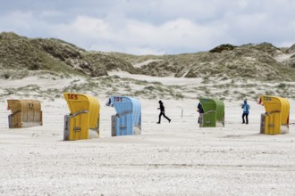 Holidaymakers walk past beach chairs on the beach of Süddorf, Insel amrum, 27.05.2021