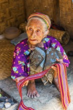 Old woman offering textiles for sale, textile, old age, human, work, colourful, clothing, village,