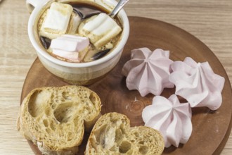 Chewing marshmallows, meringue and coffee cup on a wooden board and linen tablecloth