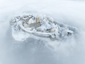 Aerial view of the Hegau volcano Hohentwiel with Germany's largest fortress ruins on a cold, foggy