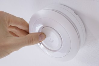 Symbolic photo on the subject of smoke alarms. A smoke detector hanging from the ceiling in a flat.