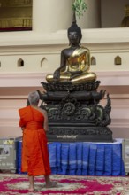 Monk in front of a Buddha statue, Bhumispara-mudra, Buddha Gautama at the moment of enlightenment,