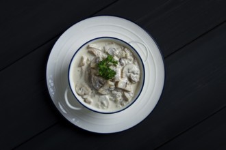 Cream sauce with mushrooms, top view, on a dark gray wooden table, horizontal, no people