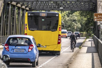 Road traffic, cycle lane, cyclist next to local bus, narrow carriageway, Raffelberg Bridge, Mülheim